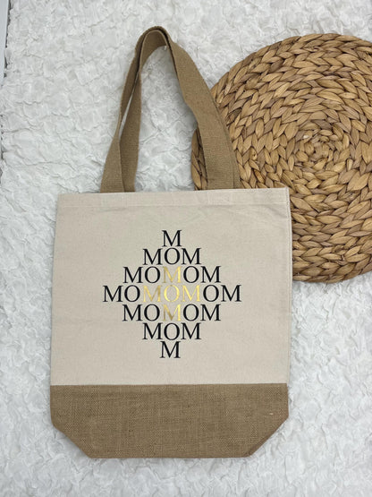 Auf dem Bild befindet sich eine Baumwolltasche, Jutetasche mit mehrfacher Mom-Aufschrift.
