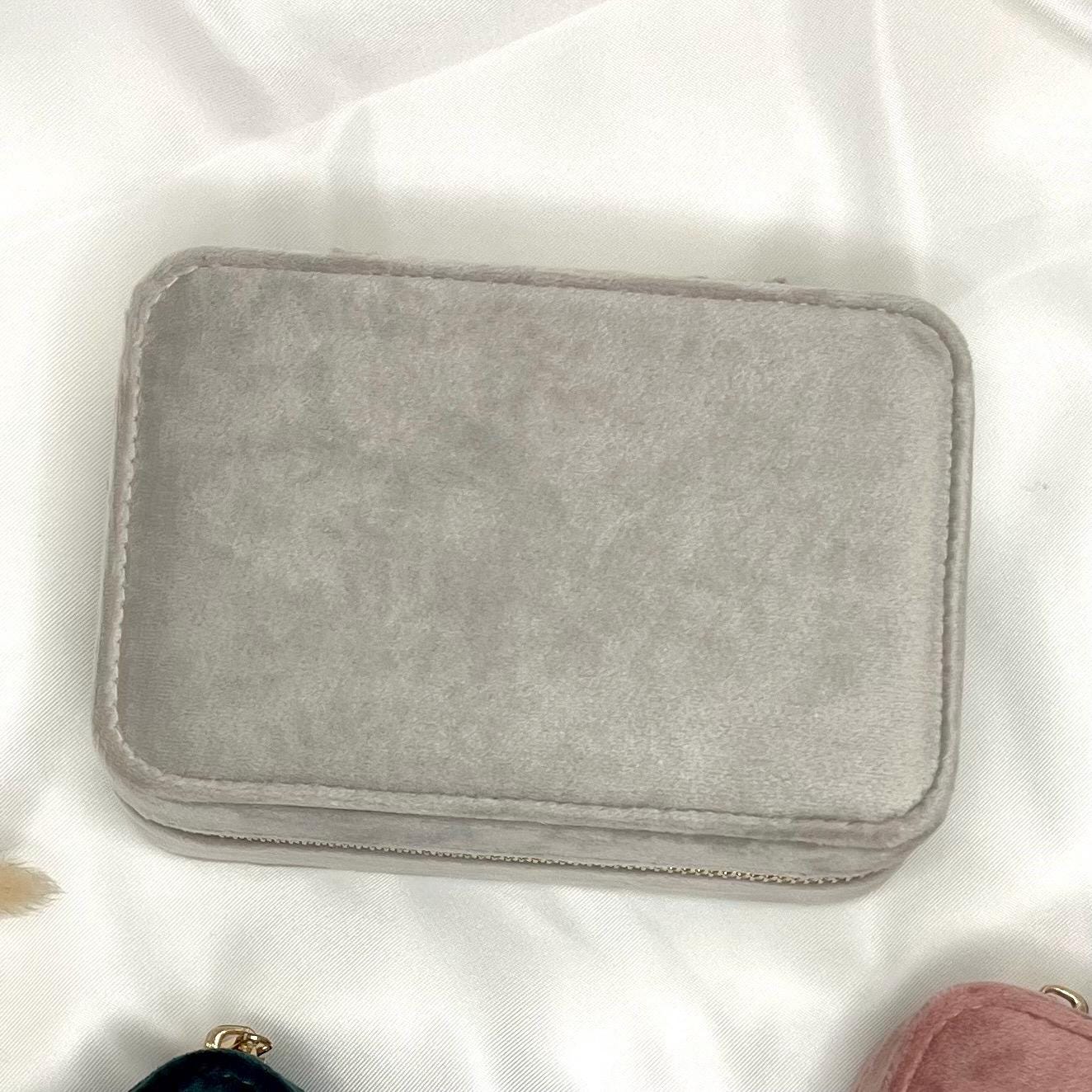 Sichere dir deine personalisierte Schmuckaufbewahrung aus 100 % recyceltem Polyester-Samtgewebe. Erhältlich in den Farben Dark Emerald, Moonstone und Rose Quartz, kannst du dein Etui mit deinem Namen personalisieren. Das kompakte Etui (15 x 10 x 5,9 cm) bietet Platz für Ringe, Ohrringe und Halsketten, mit Fächern, Haken und Samtfutter zum Schutz vor Kratzern. Der Reißverschluss und die Schieber sind goldfarben. Ein stilvolles und nachhaltiges Accessoire für deine Schmuckaufbewahrung.